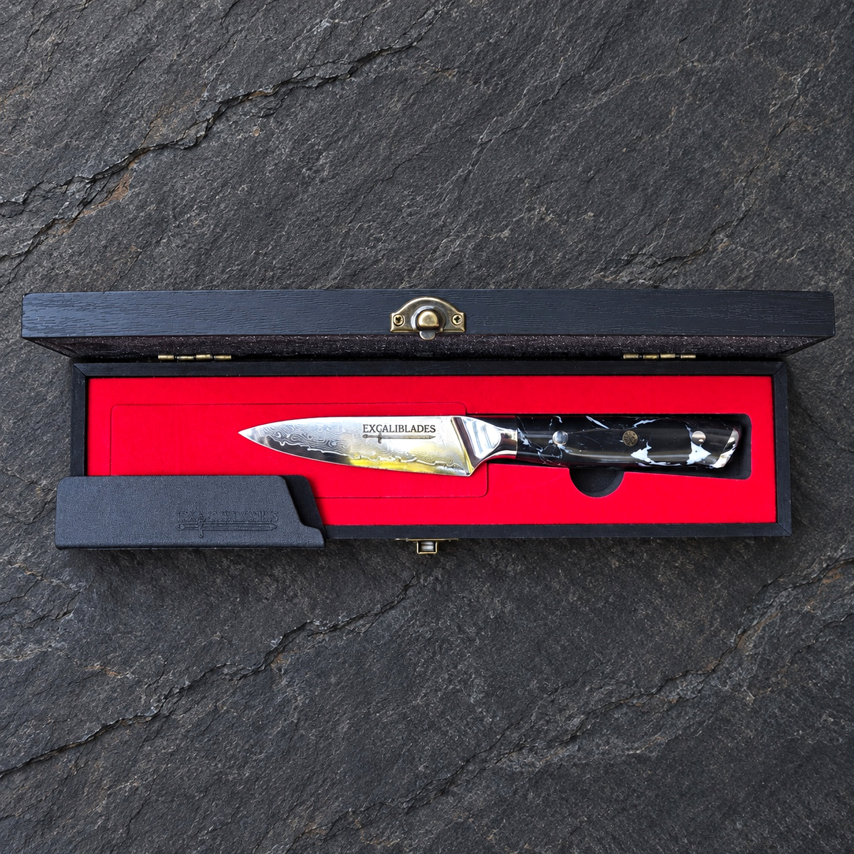 Excaliblades paring knife inside its open red-lined black wooden gift box with protective sheath