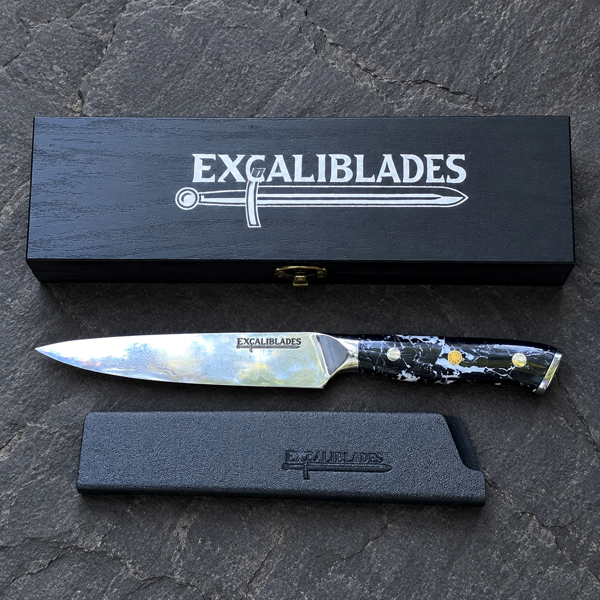 Excaliblades utility knife beside its closed black wooden gift box and protective sheath